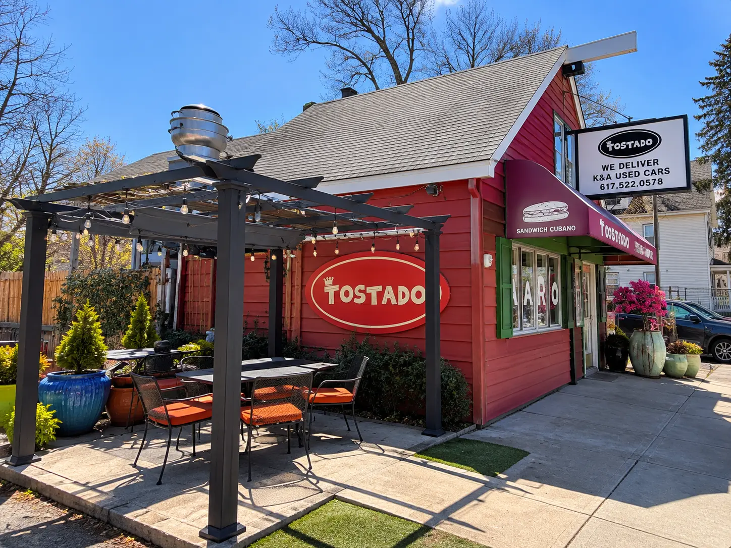 Tostado patio seating with orange chairs beside the red storefront