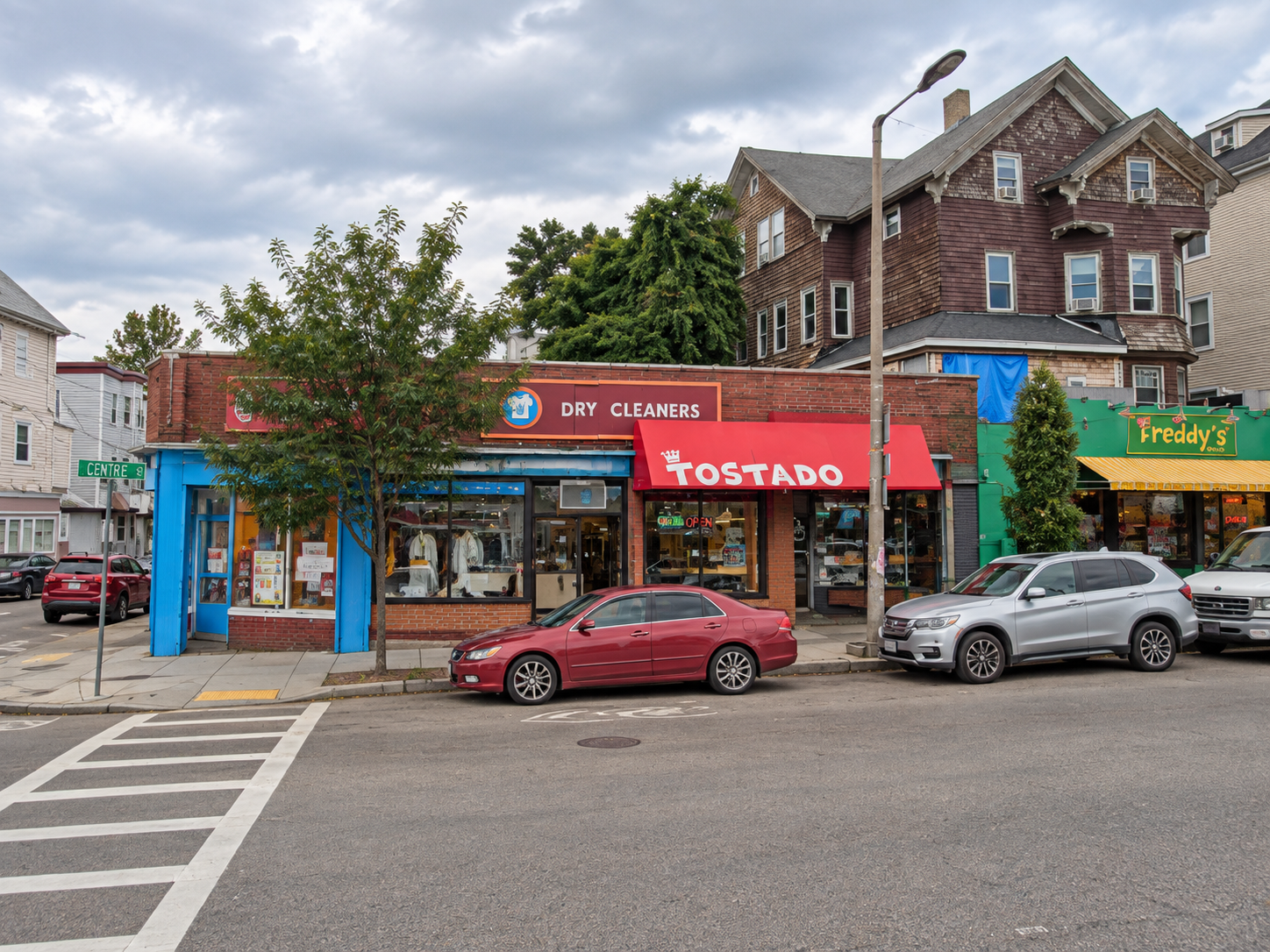 Tostado storefront on Centre Street with a red awning between neighboring shops